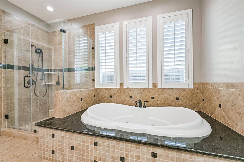 RELAXING JETTED TUBSURROUNDED BY GRANITE ANDTILE, COMPLEMENTED BY LARGEWINDOWS.