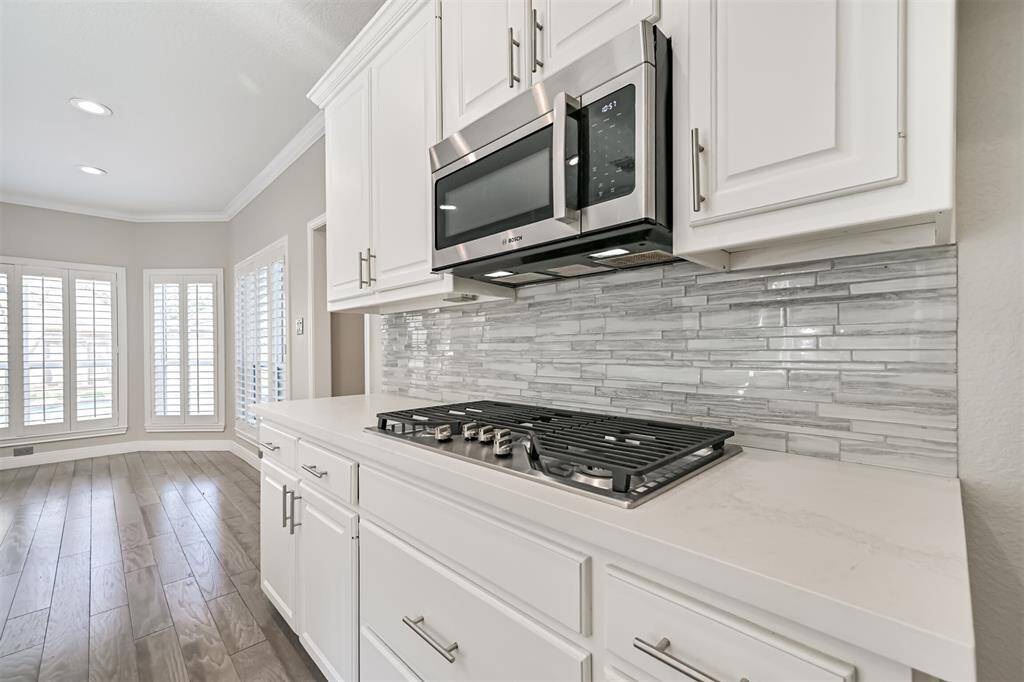 CUSTOM KITCHEN WITH GASCOOKTOP, BOSCH MICROWAVE,AND STYLISH GLASS TILEBACKSPLASH.