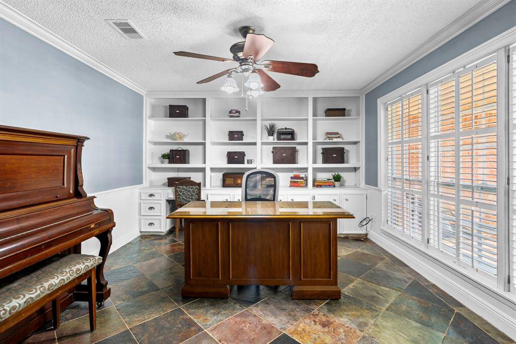 Transform your work routine into ahaven of productivity and comfort inthis thoughtfully designed homeoffice. Featuring tile floors, built-in bookshelves, ceiling fan, custom paint, and large windows with plantation shutters.