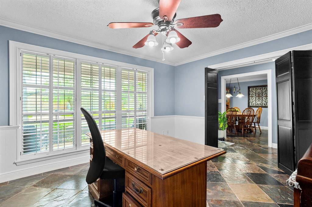 Transform your work routine into ahaven of productivity and comfort inthis thoughtfully designed homeoffice. Featuring tile floors, built-in bookshelves, ceiling fan, custom paint, and large windows with plantation shutters.