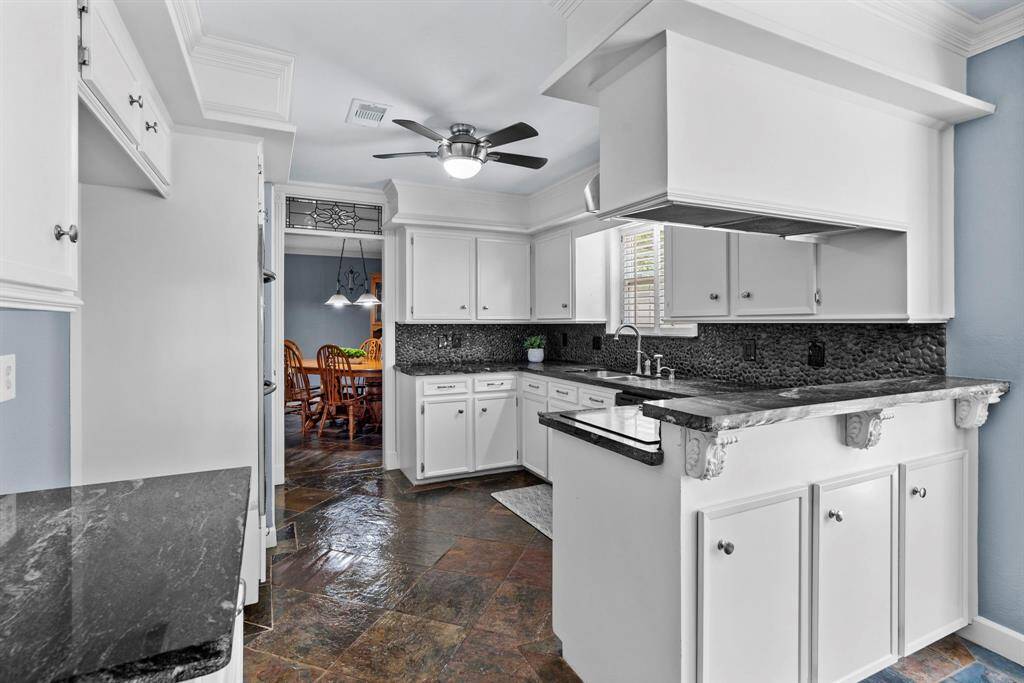 The kitchen features tile floors, white cabinets, dark countertops, and a ceiling fan.