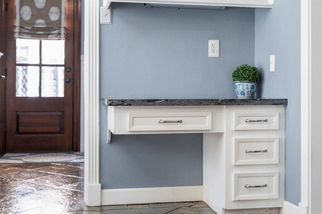 This desk area right off the breakfast room features tile floors, dark counters, and plenty of storage space.