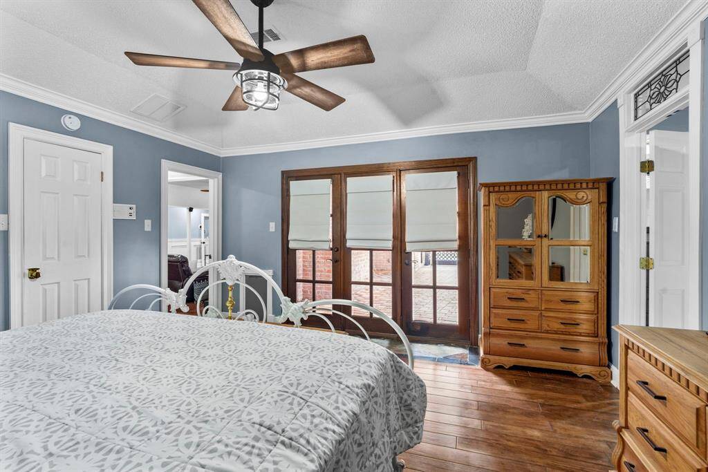The primary bedroom has beautiful flooring, ceiling fan, crown molding, and acces to the back patio.