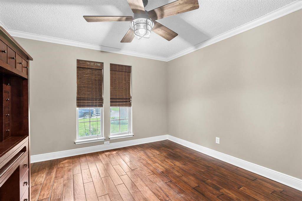 Fourth bedroom features largewindows, custom paint, crown molding, and a ceiling fan.