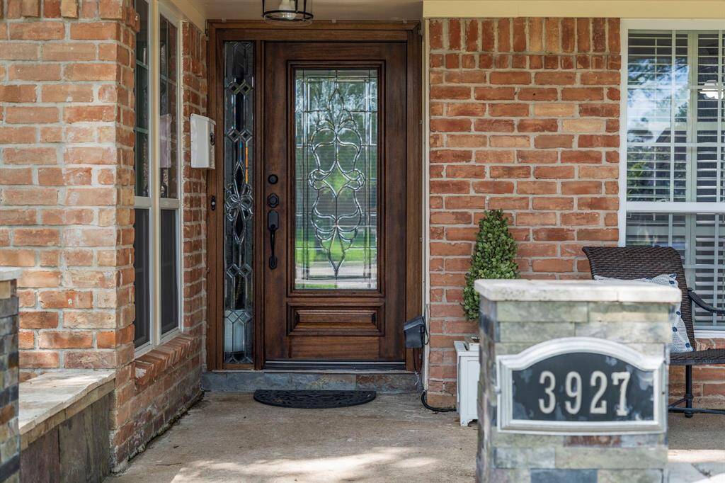 The covered front porch has a spacious sitting area and dark stained front door with glass details.