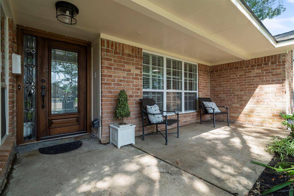 The covered front porch has a spacious sitting area and dark stained front door with glass details.