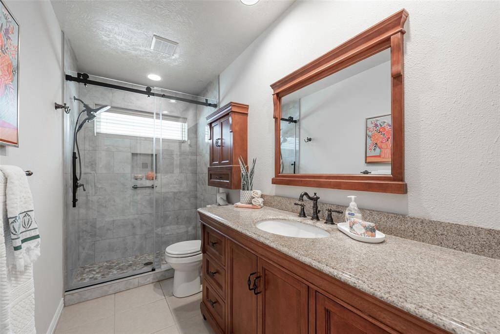 Secondary bathroom with attractive vanity & countertop. Matching wall hanging cabinet & framed mirror. Wonderfully updated walk-in shower!