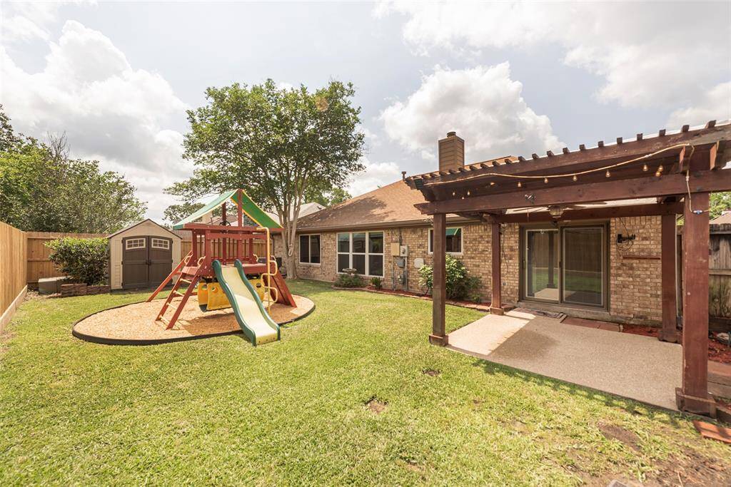 Charming backyard with storage shed, children's playset space & a pergola covered patio!