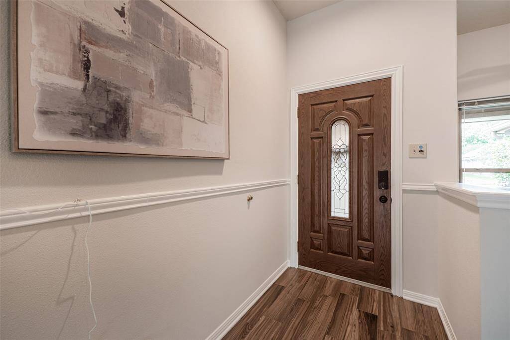 Leaded/beleved glass front door opens to wood lamniate flooring & chair-rail molding.