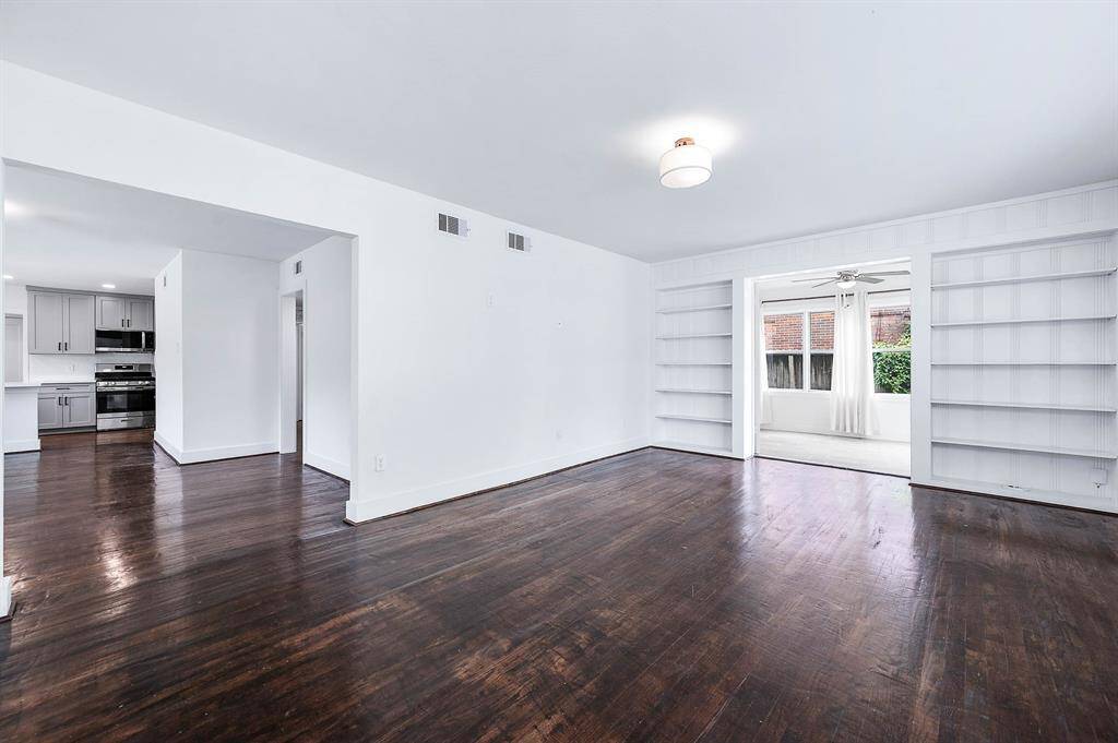 Expansive living room featuring rich hardwood floors, built-in shelving. Flows seamlessly into the kitchen and an adjacent flex room, perfect for a variety of uses.