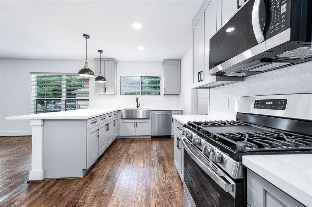 The kitchen highlights a farmhouse sink and a spacious island accented by stylish pendant lighting.