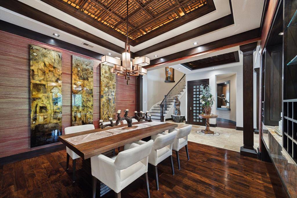 This alluring dining room seamlessly blends refined elegance with artistic expression. A dramatic wood coffered ceiling draws the eye upward, featuring an intricate lattice design and custom Lutron Radio RA2 lighting, which can be tailored to suit any mood or gathering. Thoughtful architectural framing creates a graceful connection to the grand entry and sweeping staircase, allowing the space to feel both expansive and intimate—perfect for sophisticated entertaining.