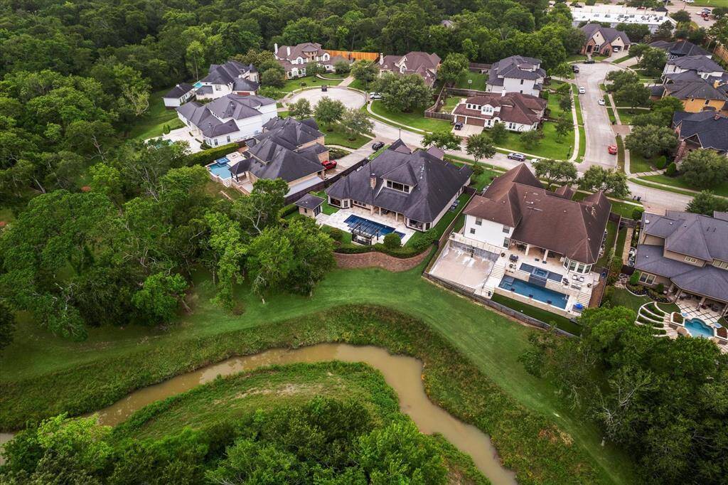 This aerial perspective highlights the home’s premium location at the curve of a tranquil cul-de-sac, backing to a lush greenbelt and gently winding creek for added serenity and privacy. The elevated lot and gracefully terraced landscaping create a distinct sense of space and seclusion, while still being seamlessly integrated into a desirable, well-established neighborhood. A true sanctuary with natural beauty just steps beyond your backyard.