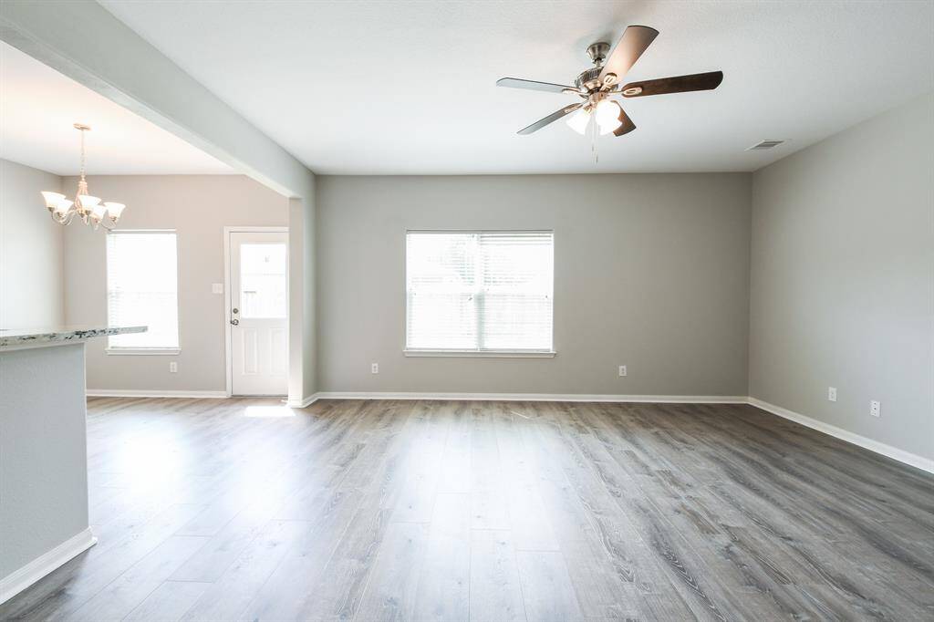 VIEW OF LIVING ROOM FROM THE FRONT ENTRANCE. NEW FLOORING, LIGHTING FIXTURES AND FRESH PAINT THROUGHOUT!