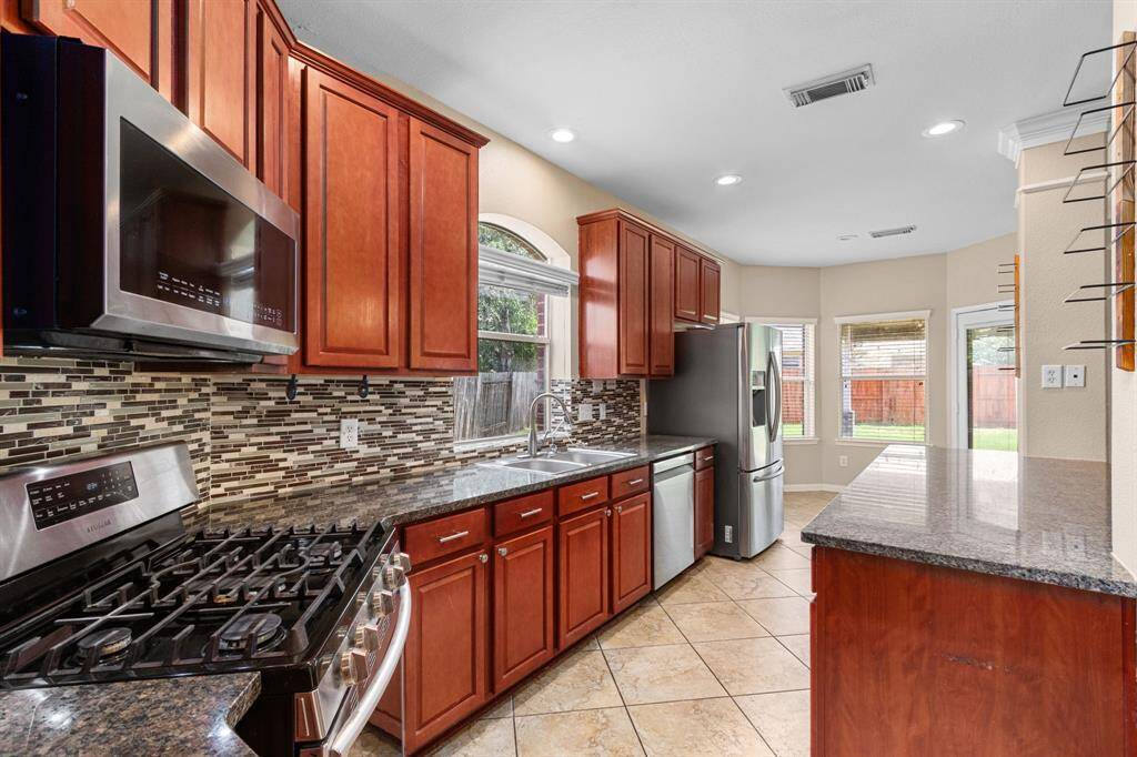 A gas range awaits the chef in the household, and the updated suite of stainless steel appliances is ready for all of your daily and special occasion meal prepping. Views to the outdoors and the living spaces of the home create a sense of connection between this functional room and the rest of the home. Expansive countertop space and spacious cabinets are both functional and attractive, with granite countertops, stainless steel hardware, and a backsplash selected for its balance of warm and cool tones.