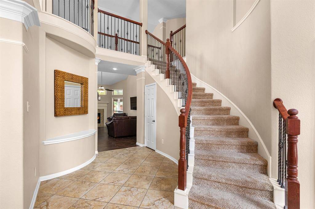 The curved staircase with wrought iron railings and soaring ceiling in the foyer create an impressive first impression as you enter the home.