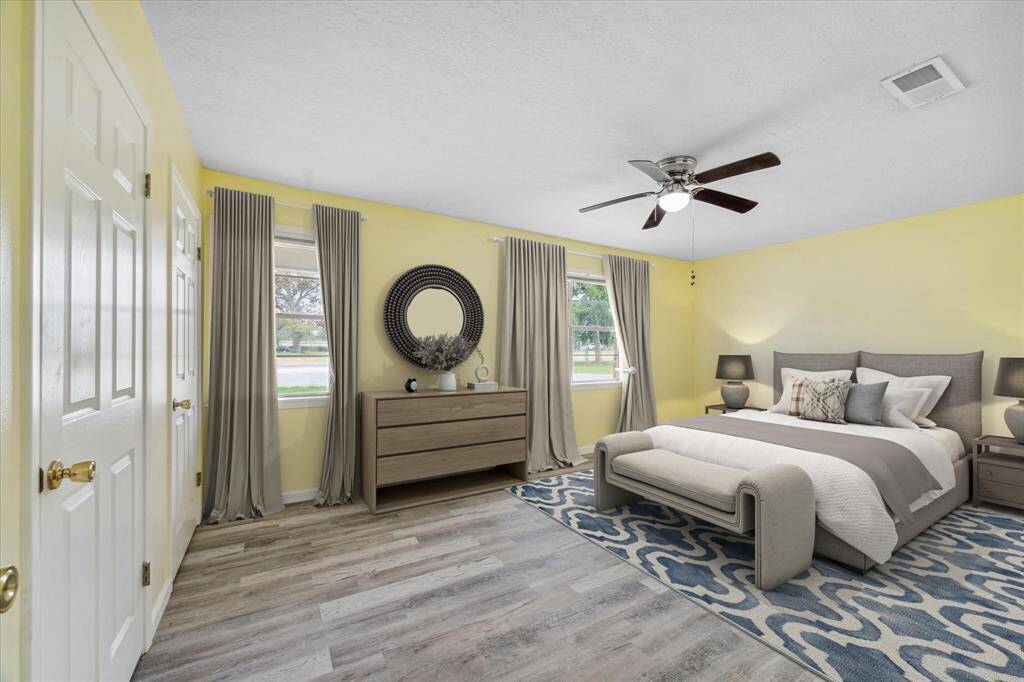 This is a compact bathroom featuring light blue walls, white cabinetry, and a subway tile shower. There's a single vanity with storage and a small window providing natural light.