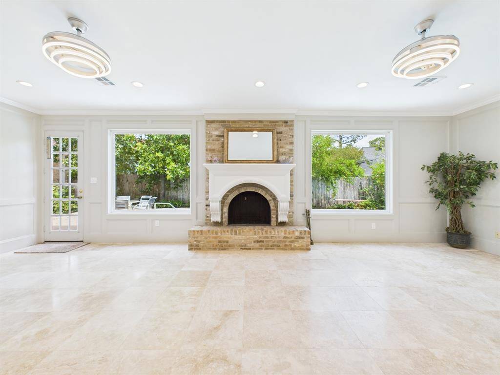 Gas Log Fireplace flanked by Windows along with Two Decorate Chandeliers that Double as Ceiling Fans