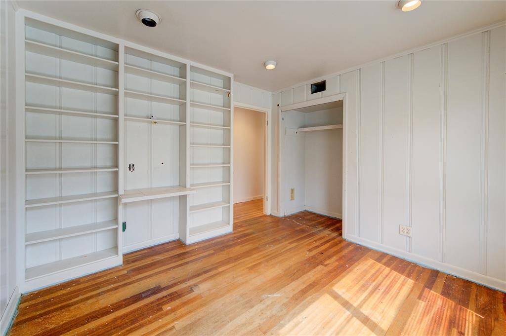 This room features built-in shelves for ample storage, hardwood floors, and a small closet. Natural light brightens the space, creating a cozy atmosphere. Perfect for a home office or study.