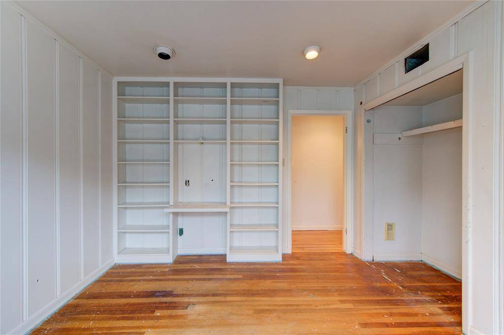 This room features built-in shelving, wood paneling, and hardwood floors, creating a cozy and functional space.