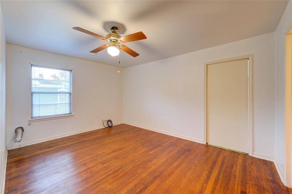 This room features hardwood floors, a ceiling fan with light, and a window for natural light. It has a neutral color palette, making it easy to personalize.