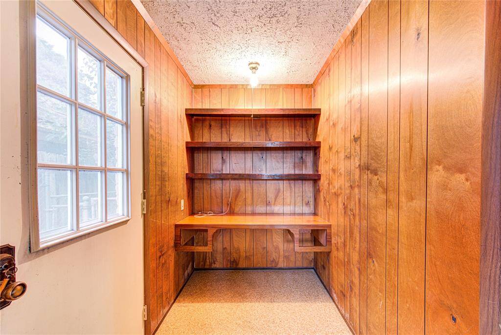 This cozy nook features wood paneling, built-in shelves, and a small desk, ideal for a compact home office space. The door with a window offers natural light.