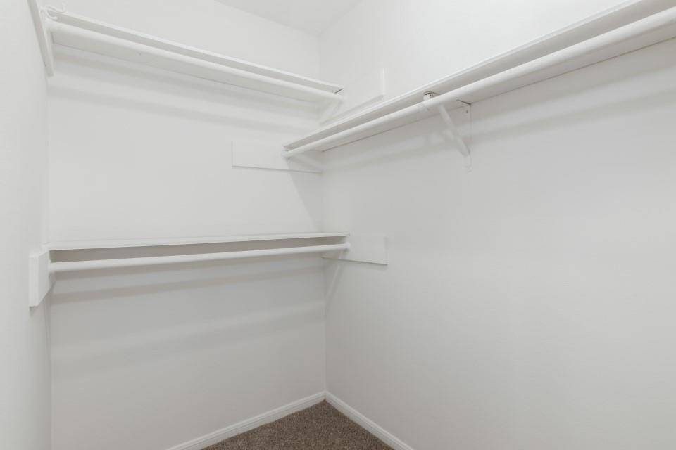 Spacious walk-in closet with multiple white shelves and hanging rods, providing ample storage space.