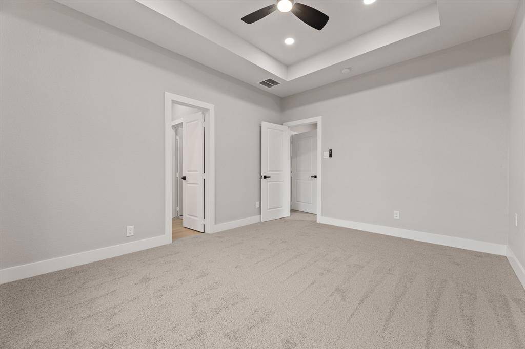 Your peaceful retreat. This spacious primary bedroom offers a relaxing sanctuary with its soft carpeting, tray ceiling, and ample natural light. The perfect space to unwind at the end of the day, with an open layout ready to be customized to fit your style.