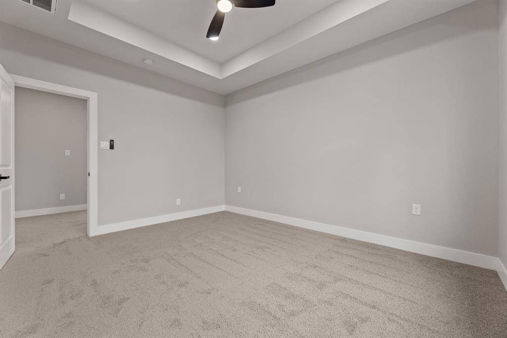 Room to relax and unwind. This spacious primary bedroom offers plenty of room for a king or queen-sized bed, with soft carpeting, a tray ceiling, and modern lighting that creates a calm and inviting atmosphere. It’s the perfect space to make your own retreat.
