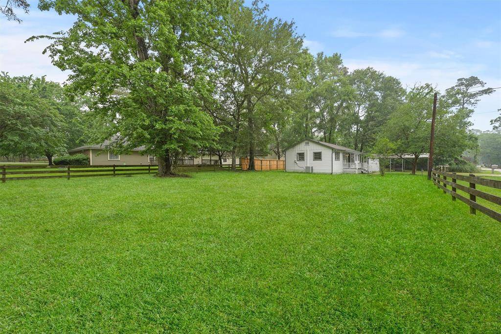 Spacious yard with mature trees, and wooden fencing, in a serene, wooded setting.
