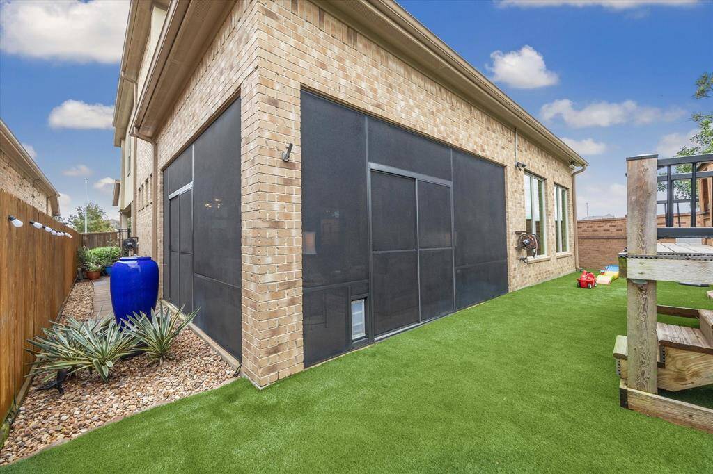 Rear Elevation with view of screened in porch and no-maintenance artificial turf yard.