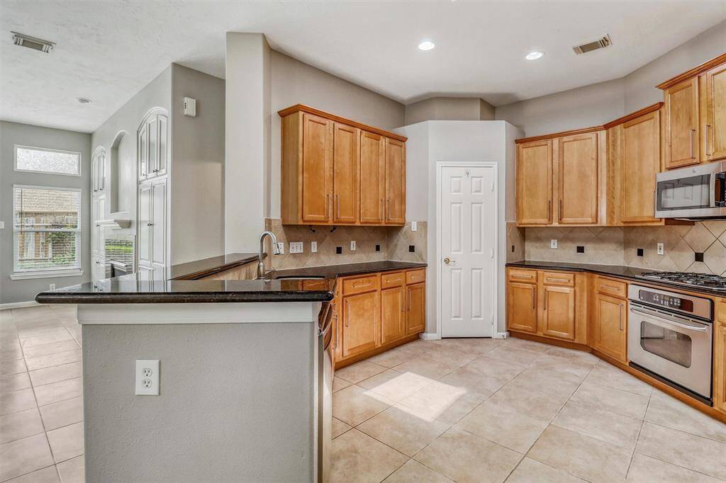 Just beyond the entryway, you'll find the heart of the home—a stunning kitchen with a spacious, open layout that's perfect for effortless entertaining. Equipped with stainless steel appliances, a large breakfast bar, and more, this kitchen is both functional and beautiful.