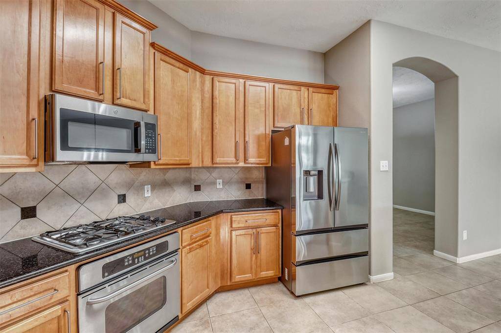 Additional highlights include a gas cooktop with a built-in microwave above for added convenience, along with a single oven below the range. The kitchen is further elevated by elegant granite countertops and a neutral backsplash, creating a timeless and stylish space.