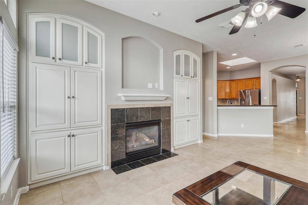 The fireplace serves as a striking accent, with a dark tile surround and an art niche above. Flanked by two custom built-ins that seamlessly blend with the central art niche, these built-ins offer ample storage for all your media equipment.