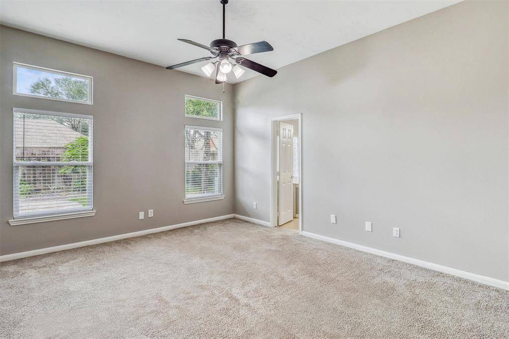 Retreat to the serene primary bedroom, complete with plush carpeting, soaring ceilings, and large windows that frame tranquil views of the backyard.