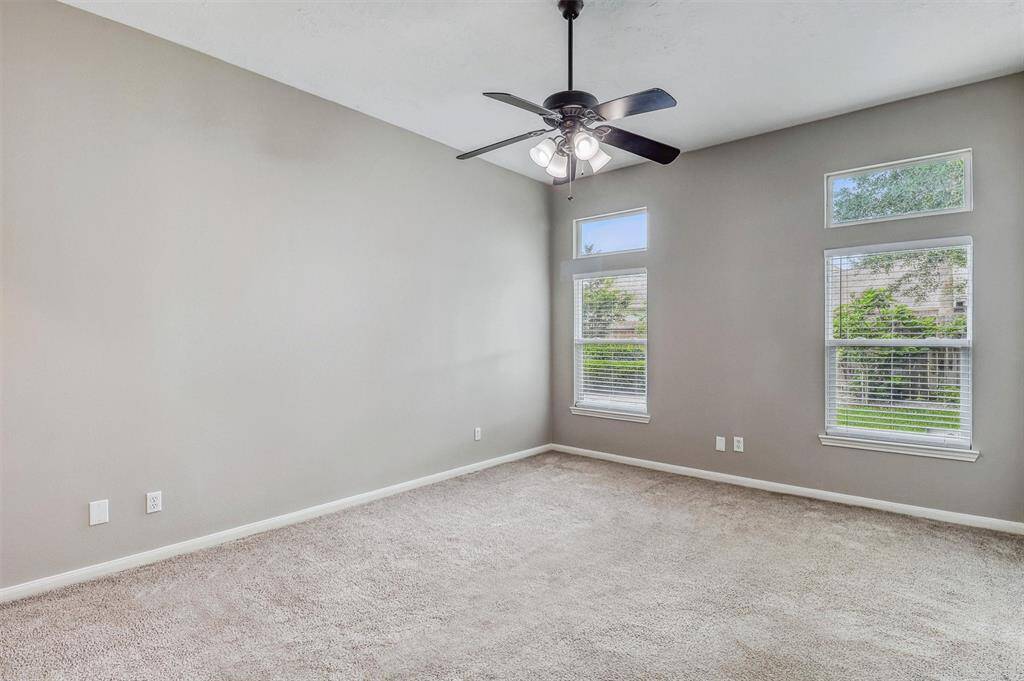 This spacious room easily accommodates a king-sized bedroom set, complemented by a ceiling fan for added comfort and air circulation.