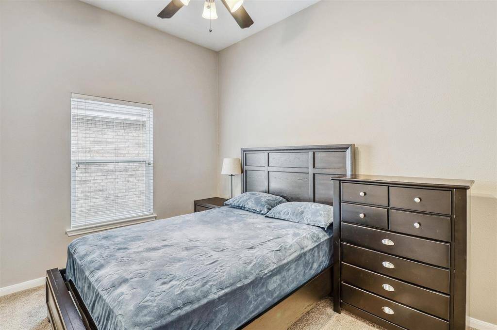 This secondary bedroom seamlessly blends comfort and style, featuring plush carpeting, decorative paint, and a large window that floods the space with natural light.