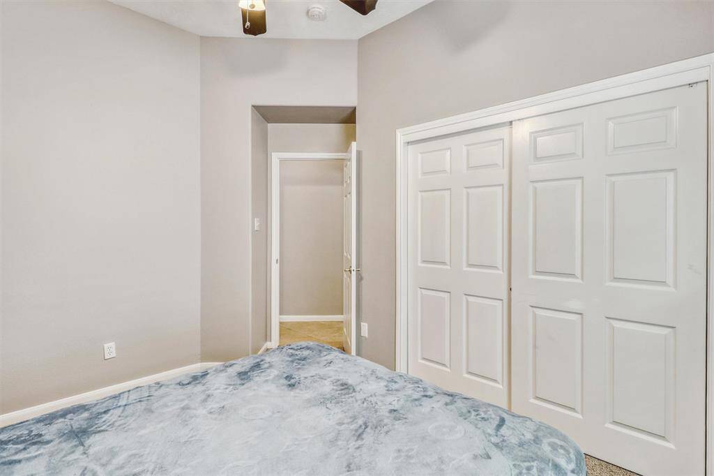 This room also features a large reach-in closet with a sliding door, along with a ceiling fan overhead for added comfort and air circulation.