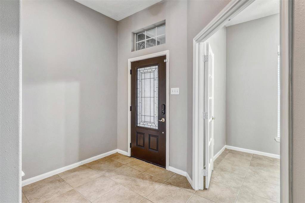 Welcome in! This elegant entryway sets the tone with soaring ceilings, large-format neutral tile flooring, and tasteful decorator paint, creating a sophisticated first impression.