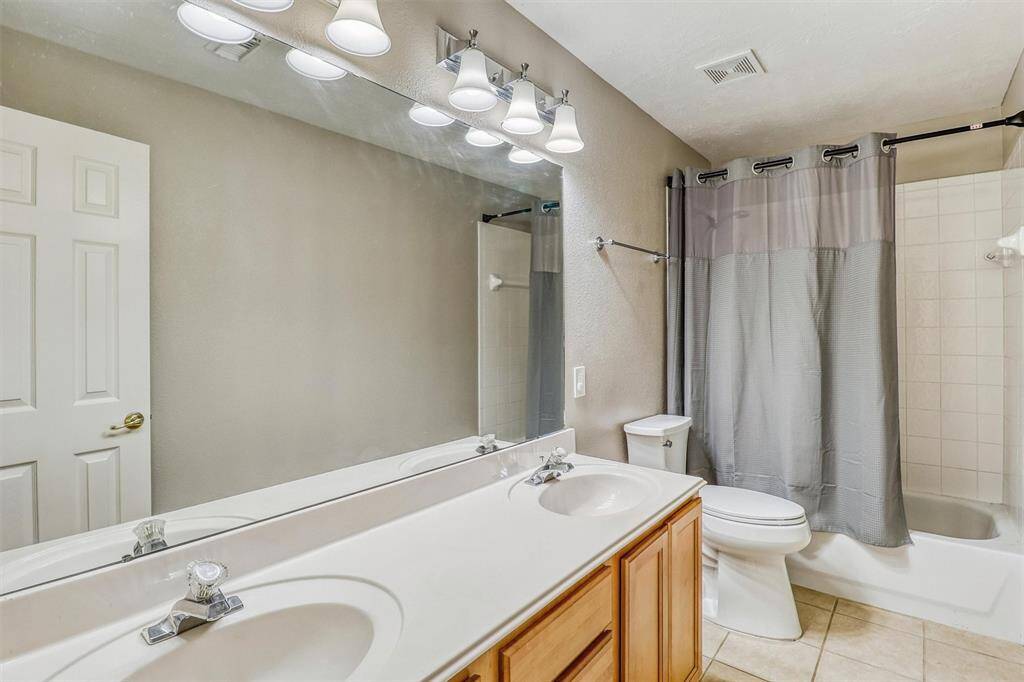 Guests will appreciate this well-appointed full bathroom, featuring a large vanity with dual sinks, stylish tile flooring, and a convenient tub/shower combination.