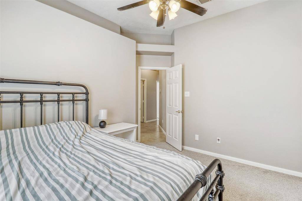 Guest bedroom number two offers plush carpeting, a ceiling fan, and a unique wall cutout near the ceiling that adds architectural dimension. There's plenty of space to comfortably accommodate a queen-sized bedroom set.