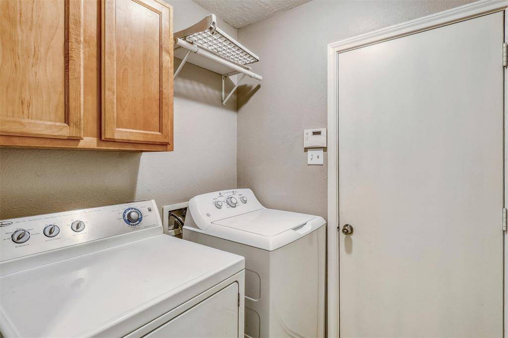 The laundry room is equipped with washer connections, built-in cabinets for storing detergents and cleaning supplies, and a shelf with a hanging rack for added convenience.