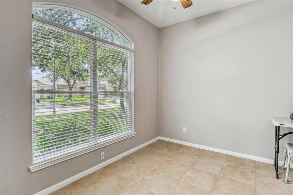 Tucked behind glass French doors, this elegant study offers a sophisticated workspace featuring tile flooring, stylish decorator paint, and a grand arched window with a beautiful view of the front yard