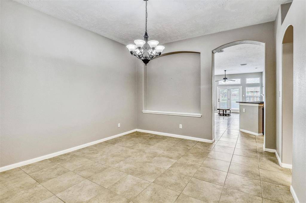 The dining area is highlighted by an elegant light fixture that draws the eye, complemented by a thoughtfully designed arched wall niche—perfect for showcasing artwork and adding architectural charm.