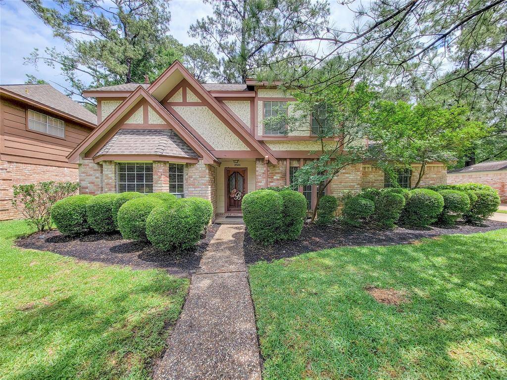 Charming two-story home with a classic brick exterior and Tudor-style accents. It features a well-maintained front yard with neatly trimmed hedges and a paved walkway. Surrounded by mature trees, the property offers a sense of privacy and tranquility.