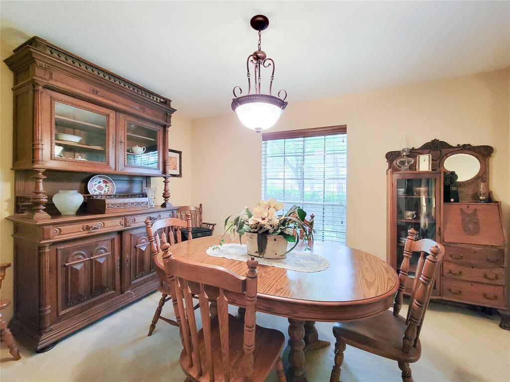 The dining room is warmly lit by an elegant chandelier and has a window with blinds for natural light. Perfect for intimate gatherings.
