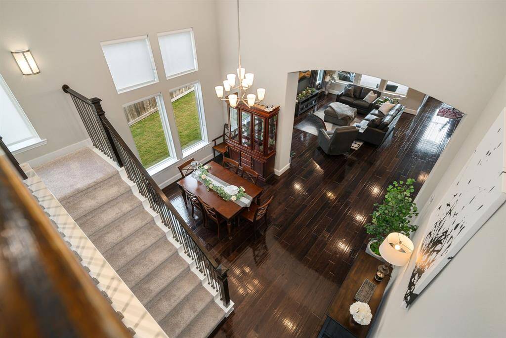 View from upstairs looking down to the dining and living room. A dramatic staircase leads to the 1/2 story upstairs for access to the movie theater and the 1/2 bath.