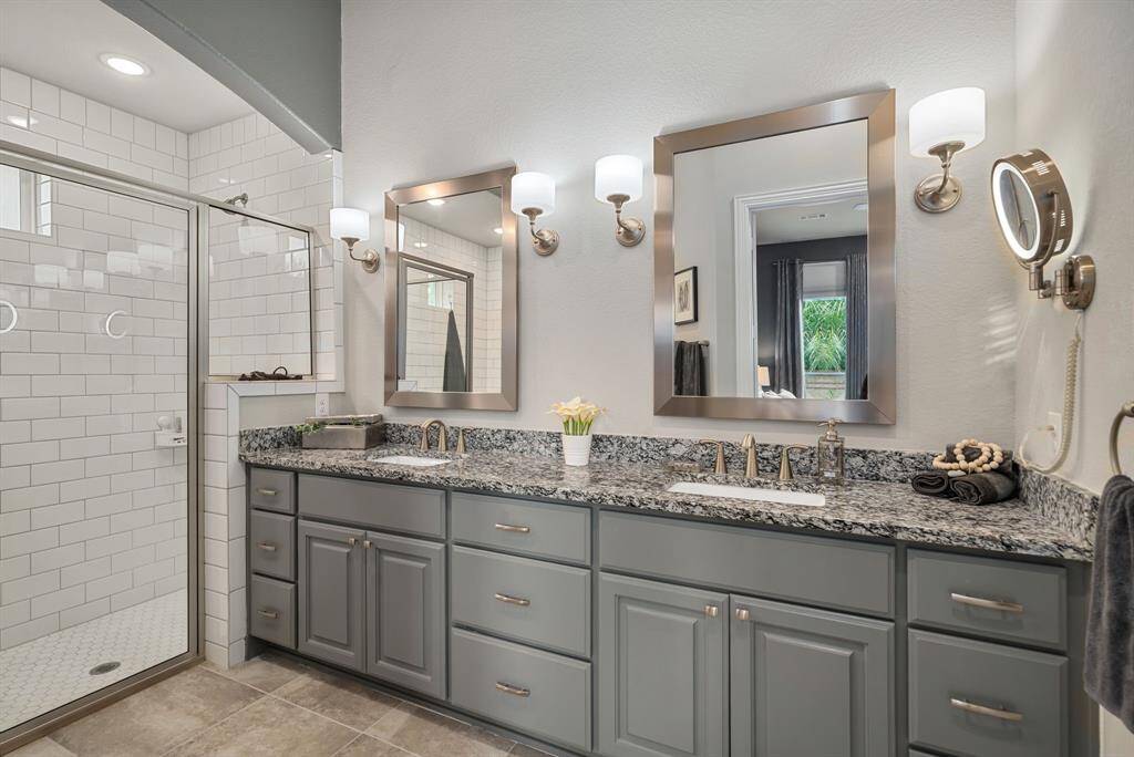The primary bath features dual sinks, custom mirrors, and lighting with ample storage.