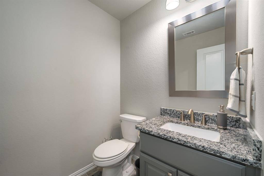 Powder bath upstairs outside the media room with designer mirror, granite countertop and brush nickel fixtures.