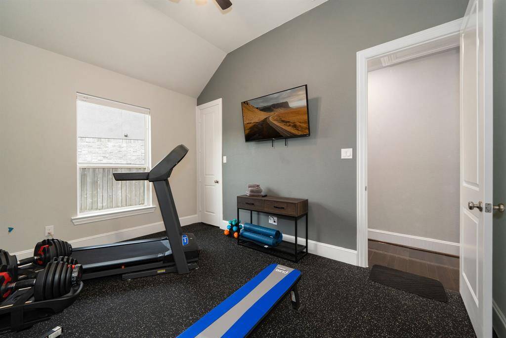 Secondary bedroom with high ceilings currently being used as an in-home fitness area.